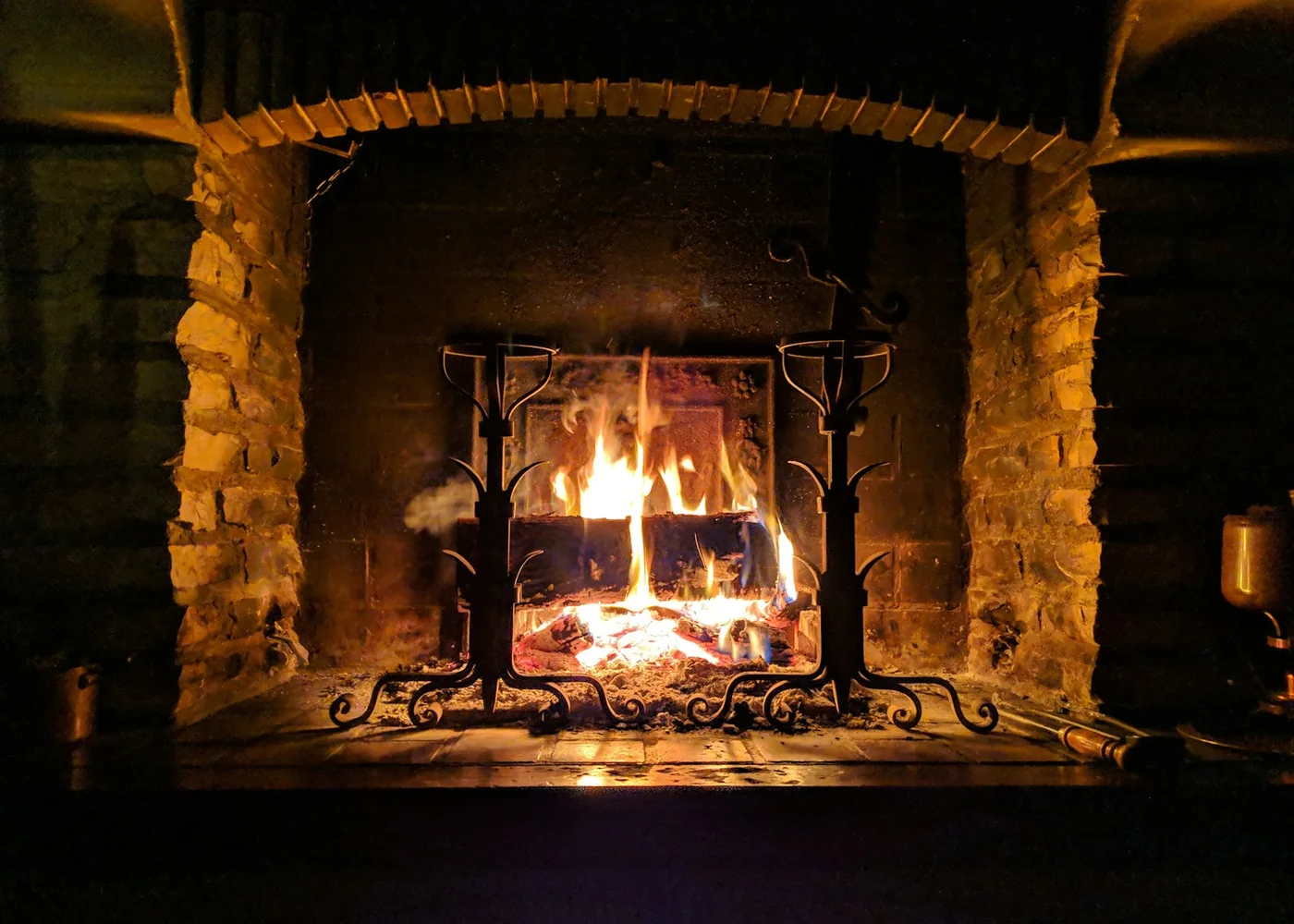 Llar de foc encesa amb la llenya apilada al costat